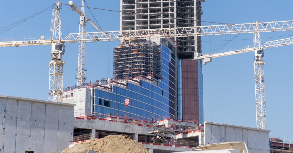 High-rise construction site with multiple cranes against blue sky