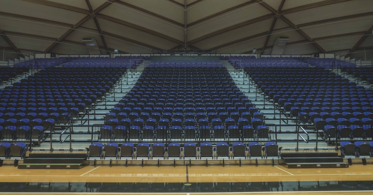 Empty NBA-style basketball arena with court visible and rows of seating